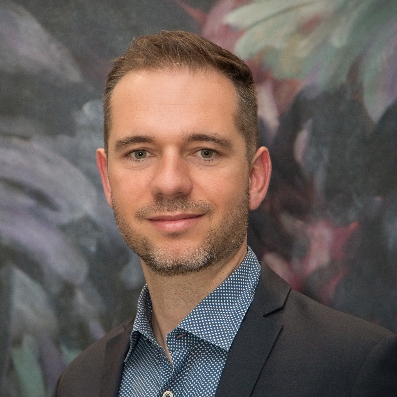 Alberto Lusoli, Assistant Professor, against a blurred artistic background.